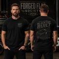 Two men wearing black t-shirts with 'Forged Flag Society' branding in a garage setting.
